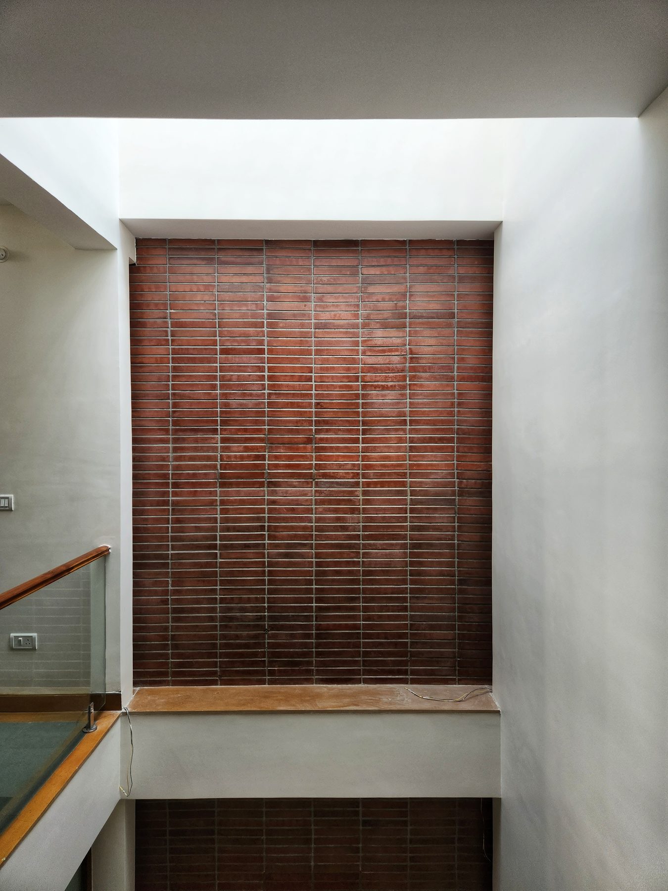 House of Volumes — The brick wall in the skylit void